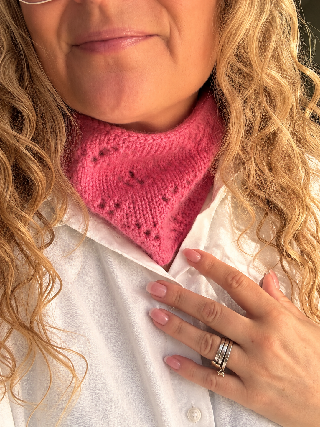  nærbilde med hvit skjorte: Rosella Cowl fra Leneknit, rosa strikket hals med hullmønster, brukt til hvit skjorte.